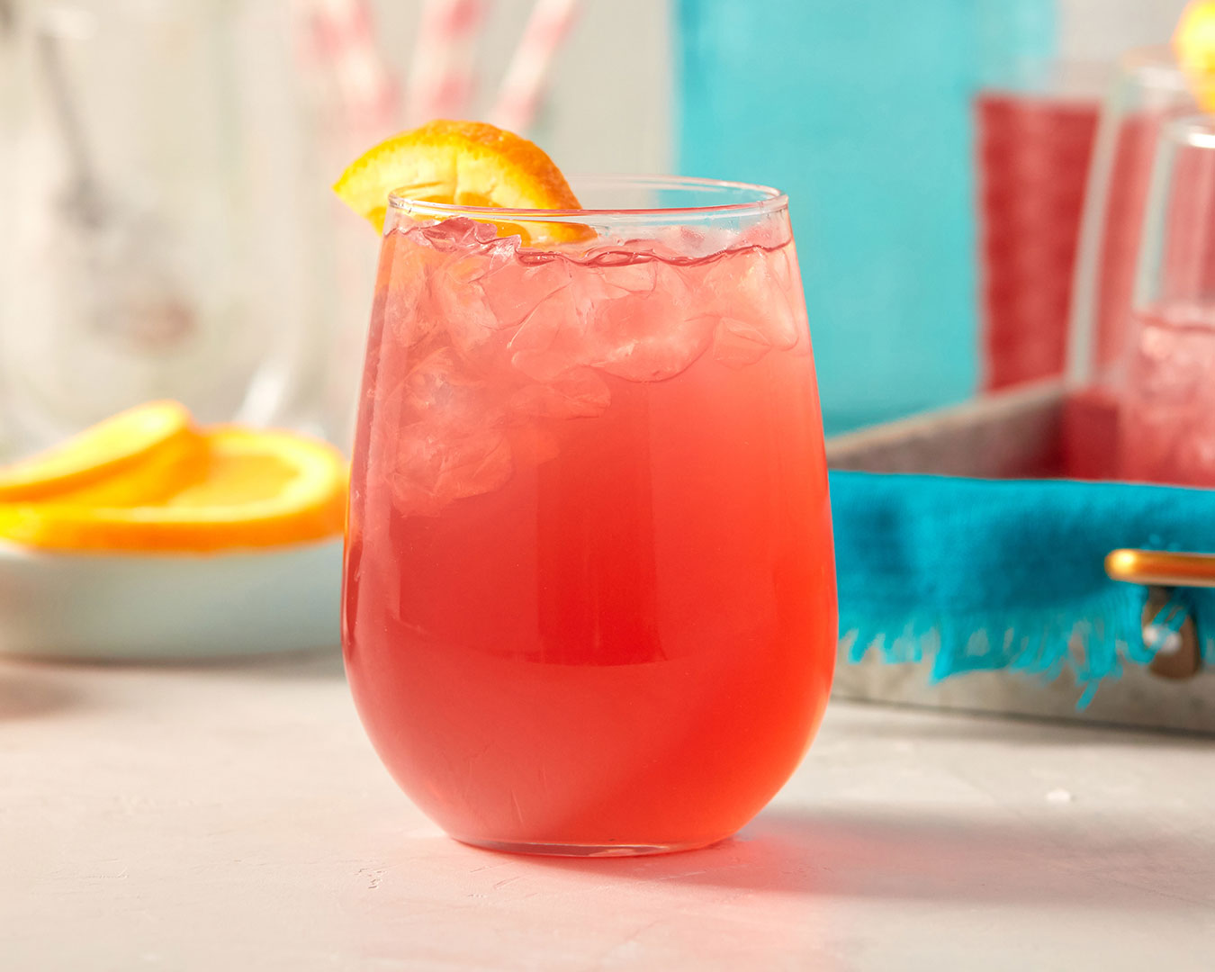 Red pink drink with oranges and summer colored background photographed by food and beverage photographer Kate Benson.