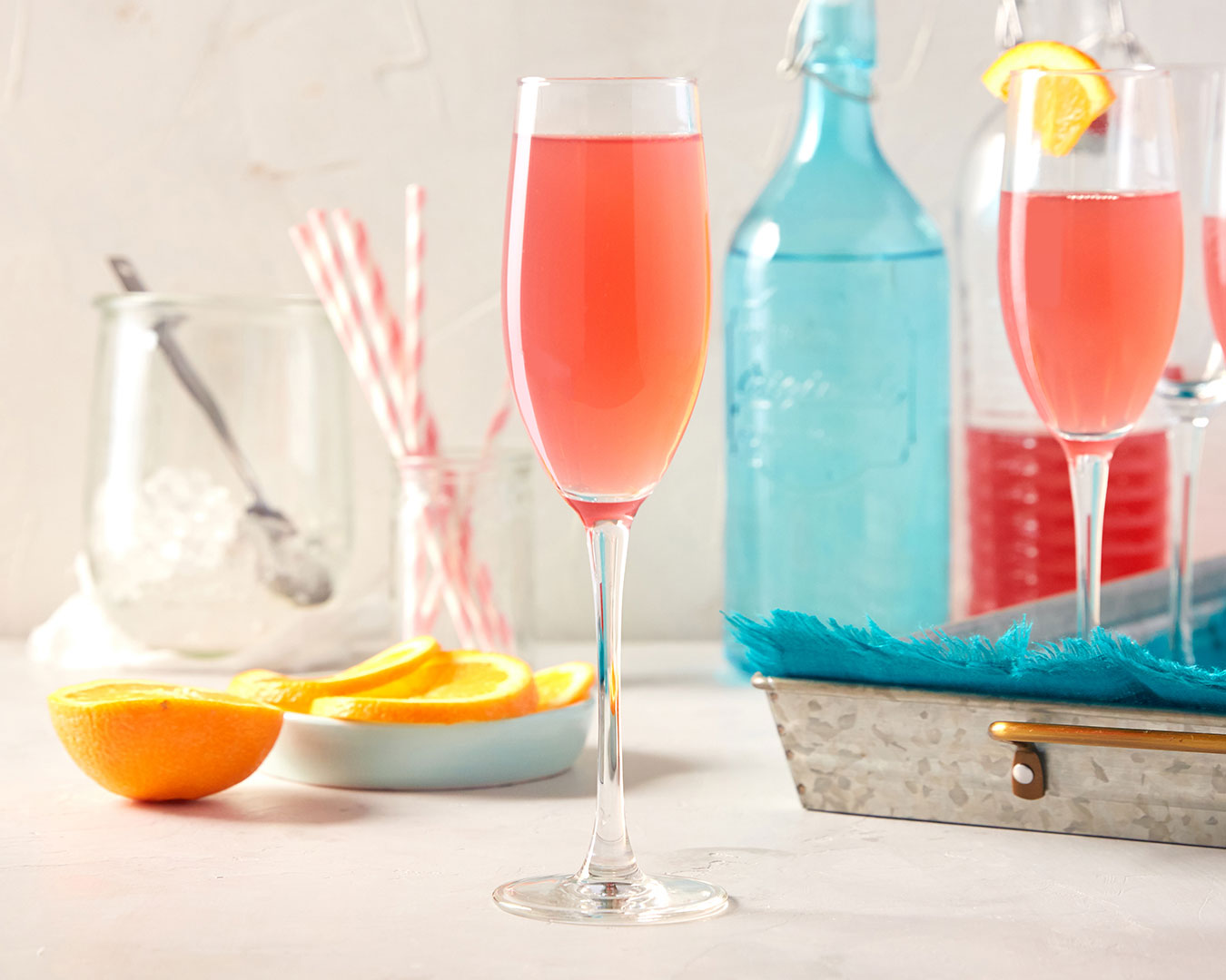 Pink drink with tray, oranges, and straws in background, photographed by Kate Benson, professional food and beverage photographer.