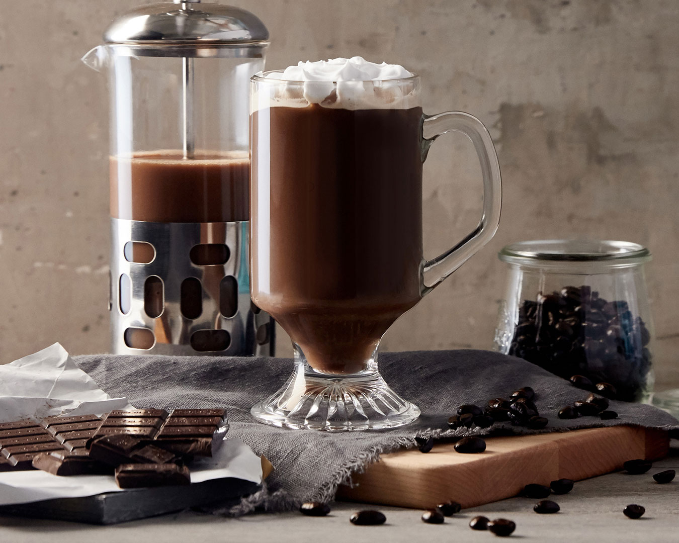 Mocha coffee with coffee press, coffee beans, and chocolate photographed by professional food and beverage photographer Kate Benson.