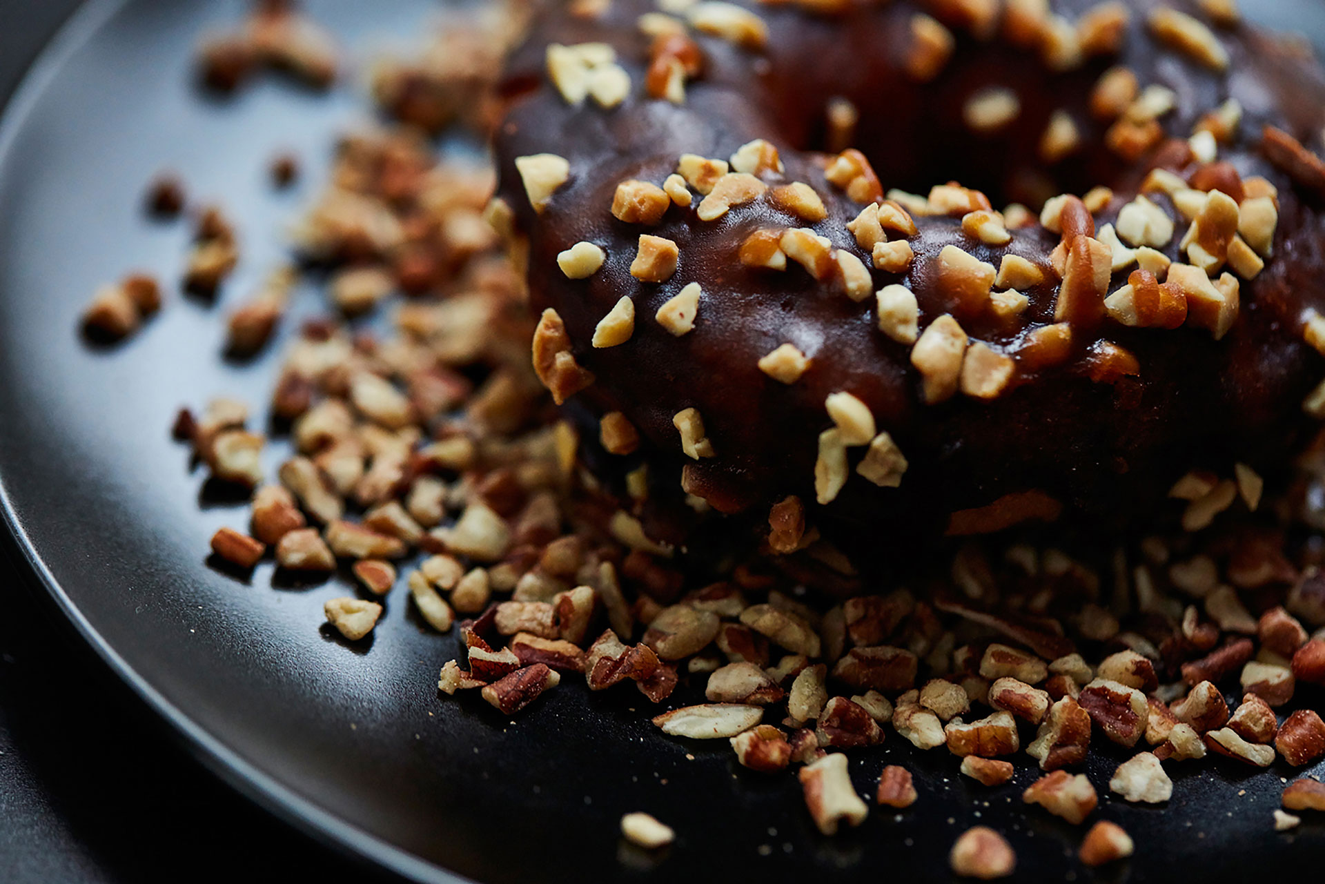 Chocolate donut sprinkled with nuts photographed by food and beverage photographer Kate Benson.