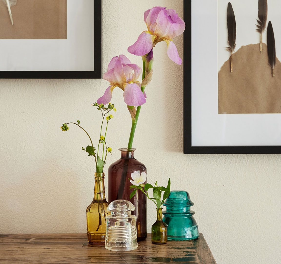 Antique glass bottles with floral arrangements styled and photographed by still life photographer Kate Benson.