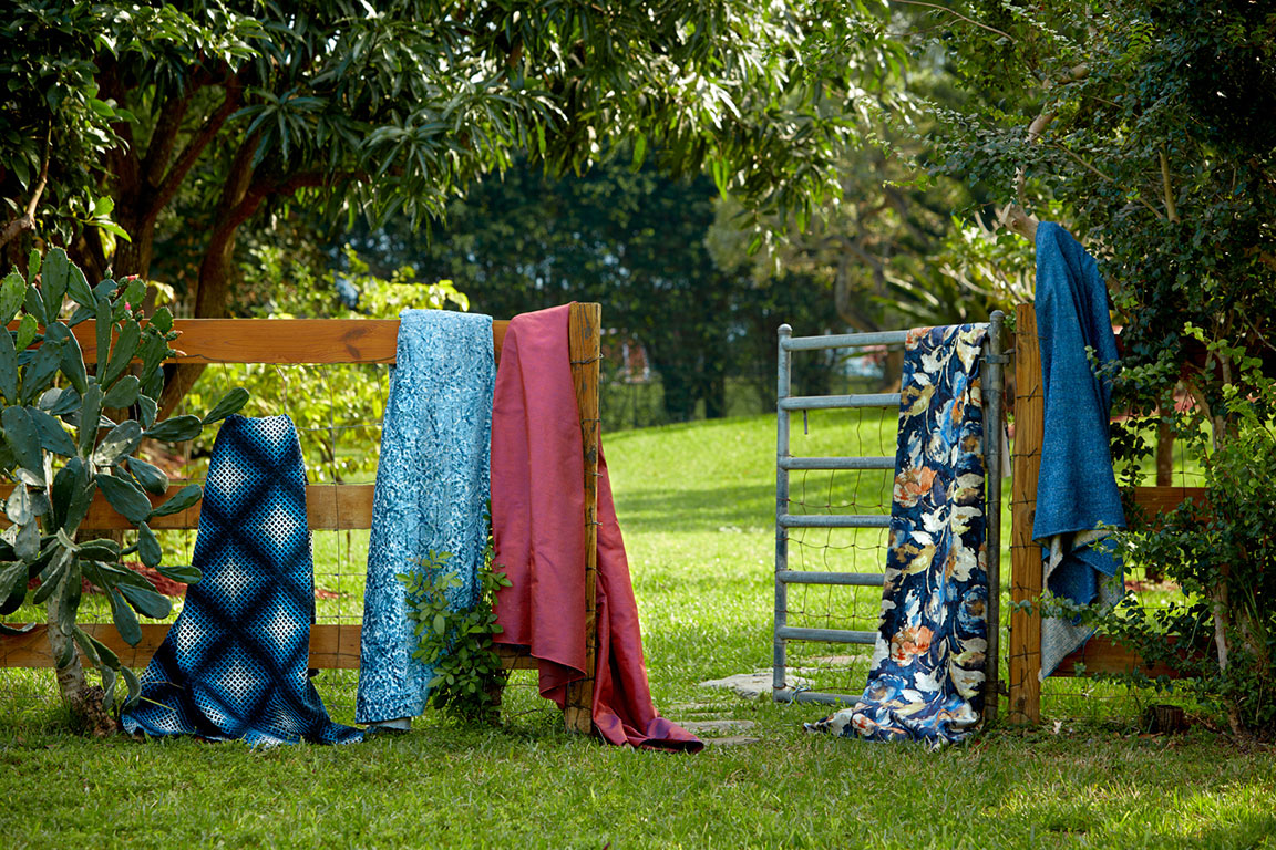 Fabrics folded over fence in park photographed by professional still life photographer Kate Benson.