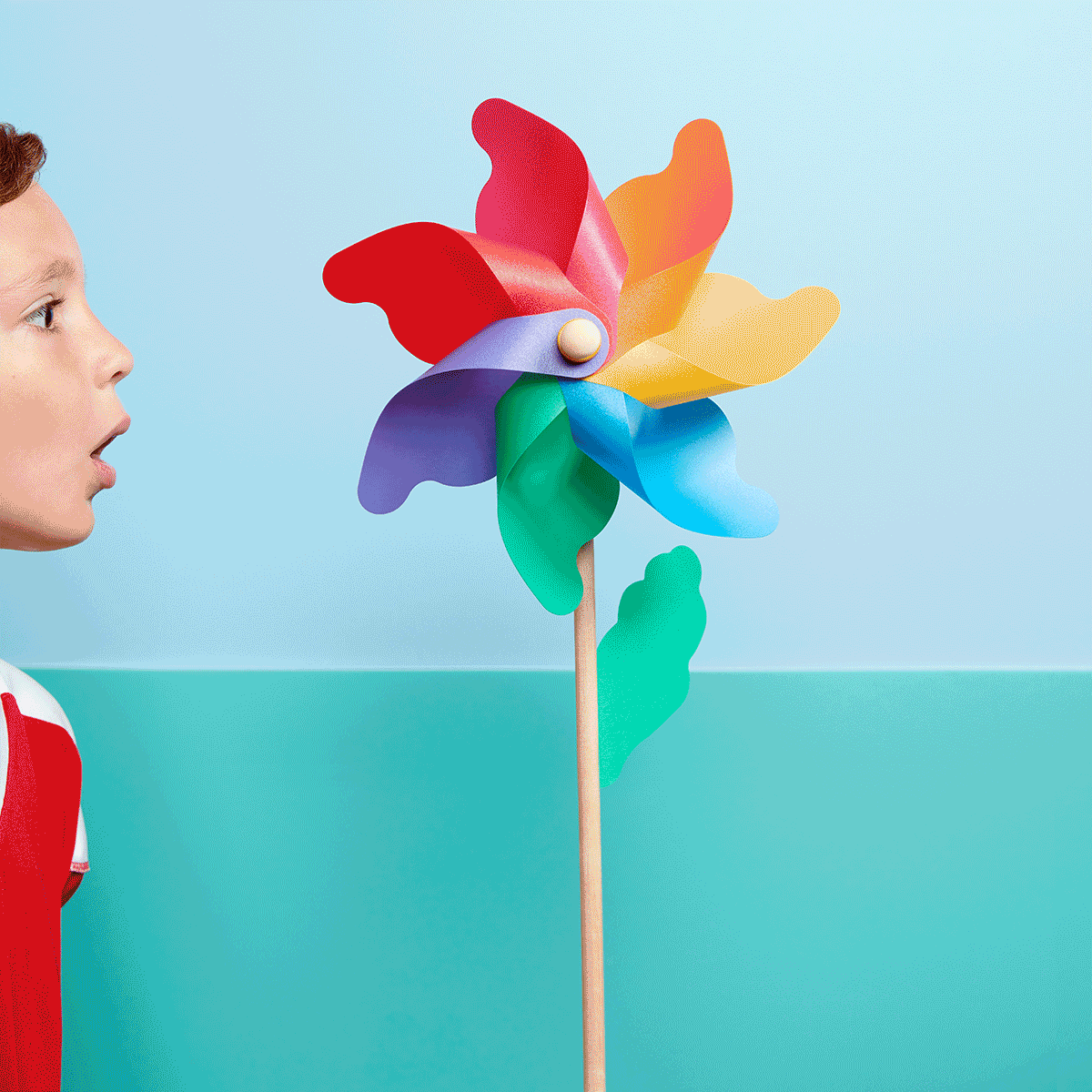 Child blowing on pinwheel photographed by product photographer Kate Benson.