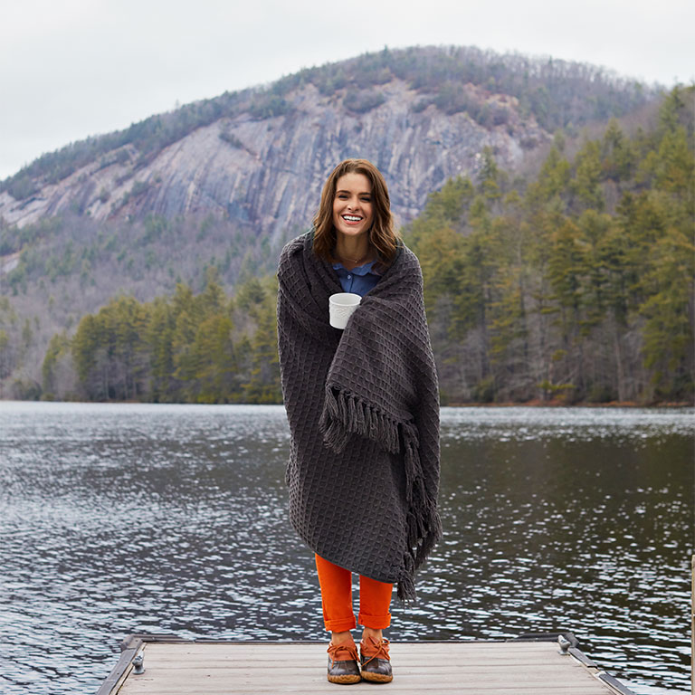 Professional model standing on dock by lake photographed by fashion commercial photographer Kate Benson.