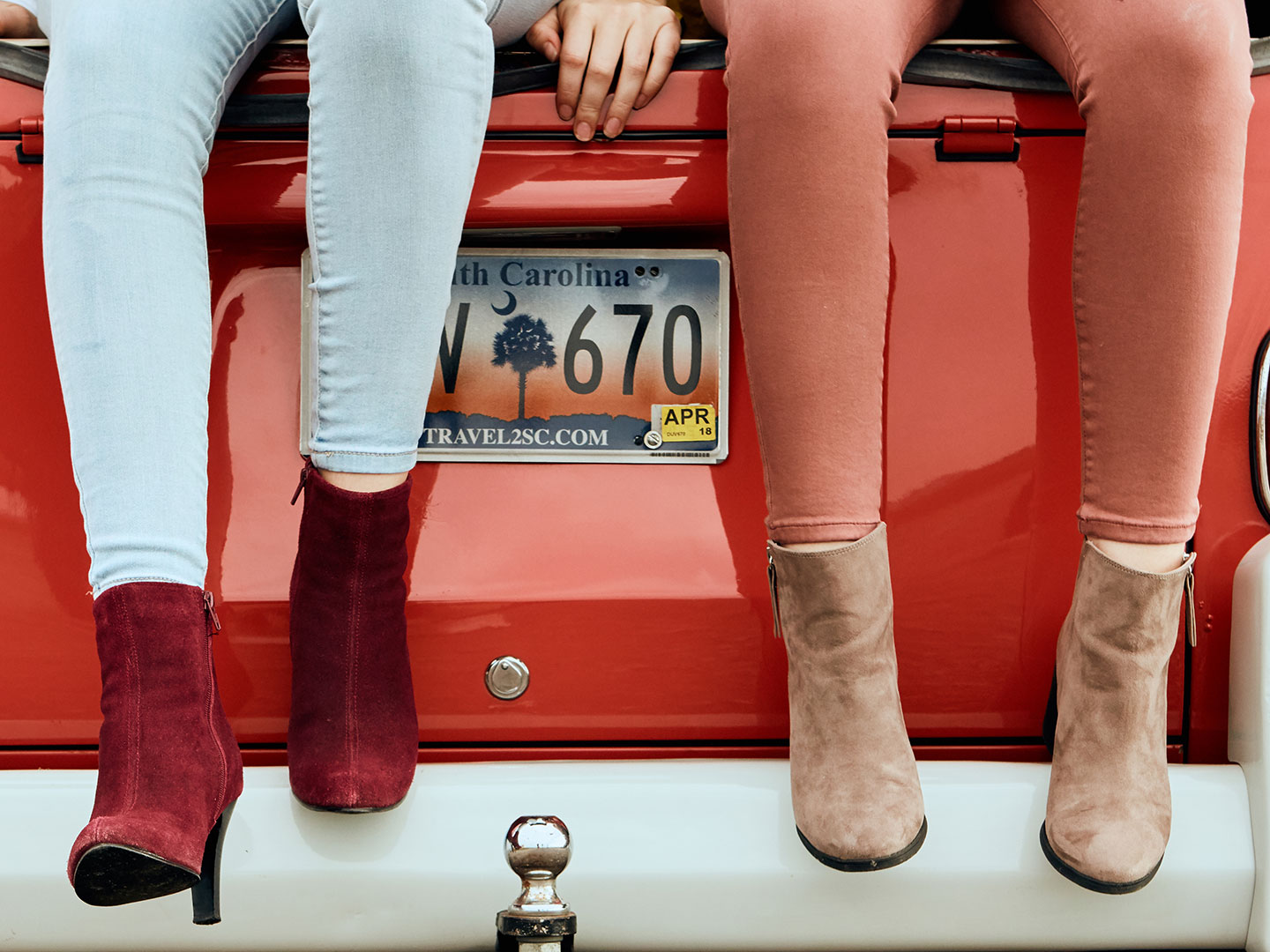 Models legs and feet dangling from back of a car photographed by footwear photographer Kate Benson.