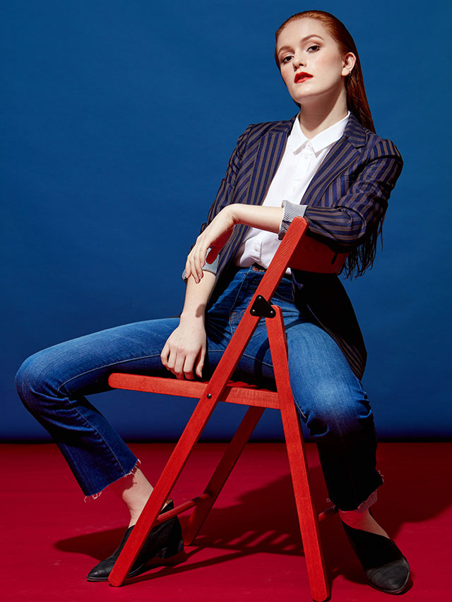 Fashion model sitting in chair with red and blue background photographed by professional advertising photographer Kate Benson.