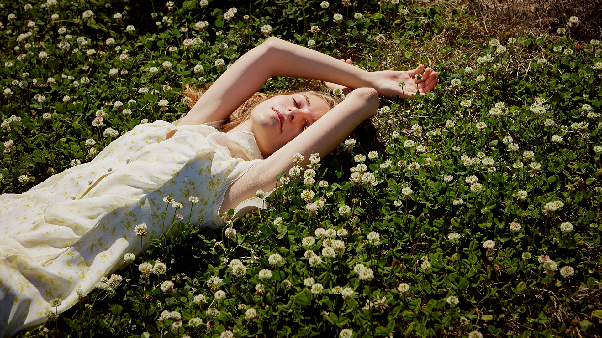 Model laying in field of clover flowers photographed by fashion apparel photographer Kate Benson