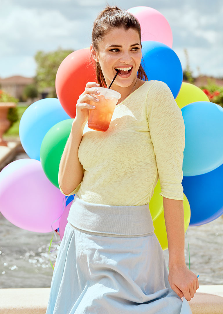 Model with cool drink and balloons in background photographed by professional fashion photographer Kate Benson.