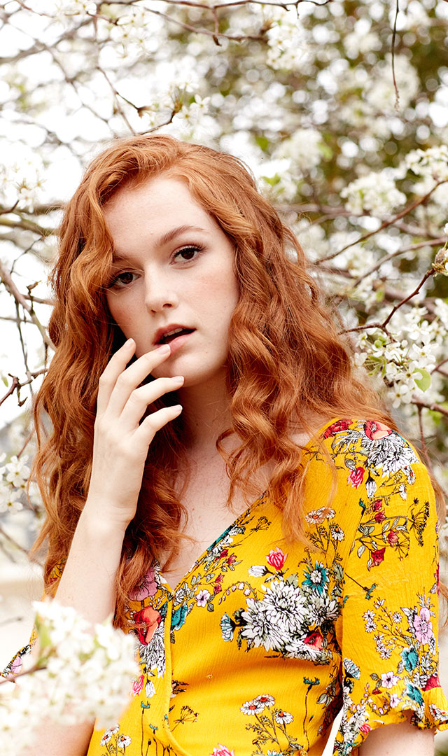 Clothing model closeup in floral dress with floral background by professional fashion photographer Kate Benson.