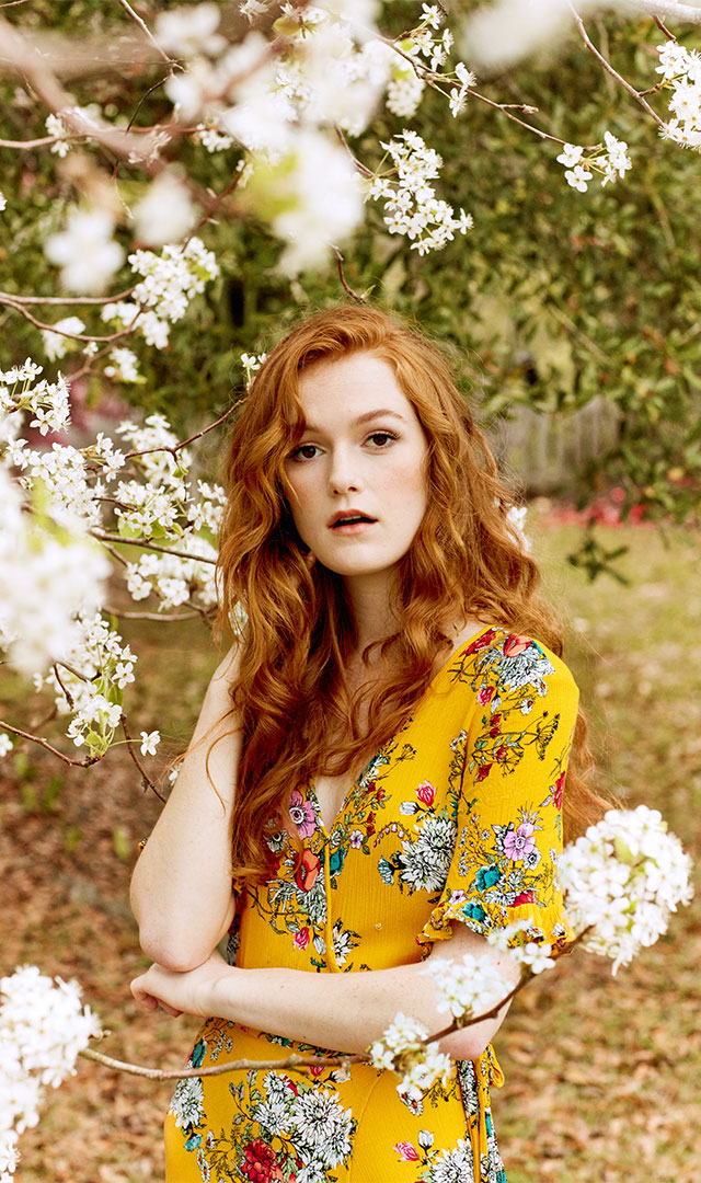 Fashion model in floral dress under tree in bloom photographed by clothing apparel photographer Kate Benson.