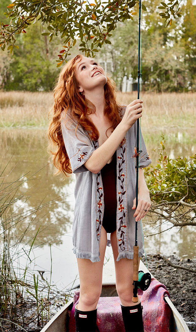Professional model with fishing rod in canoe photographed by fashion lifestyle photographer Kate Benson.